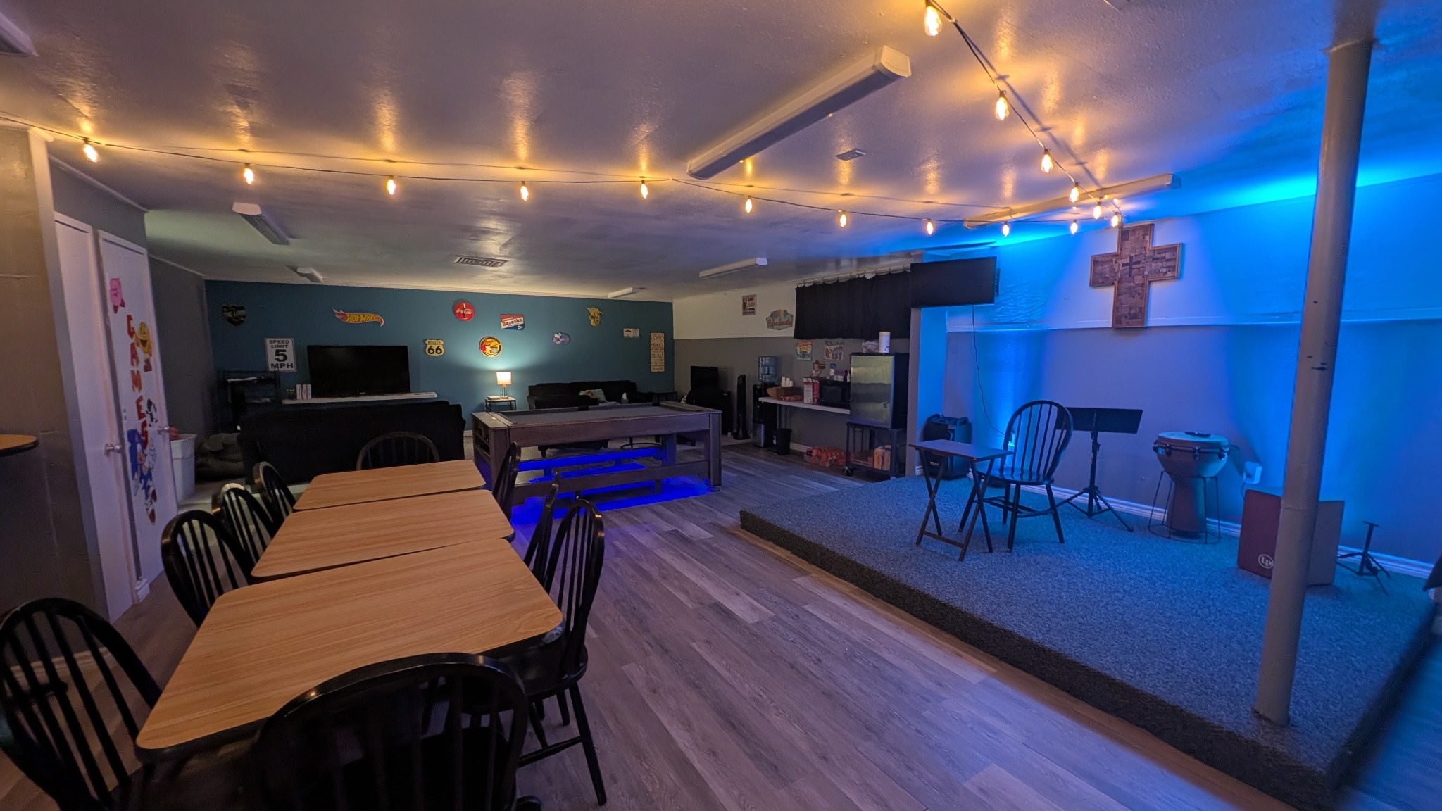 The FBC student room with string lights, blue stage lighting, sofas, and a pool table