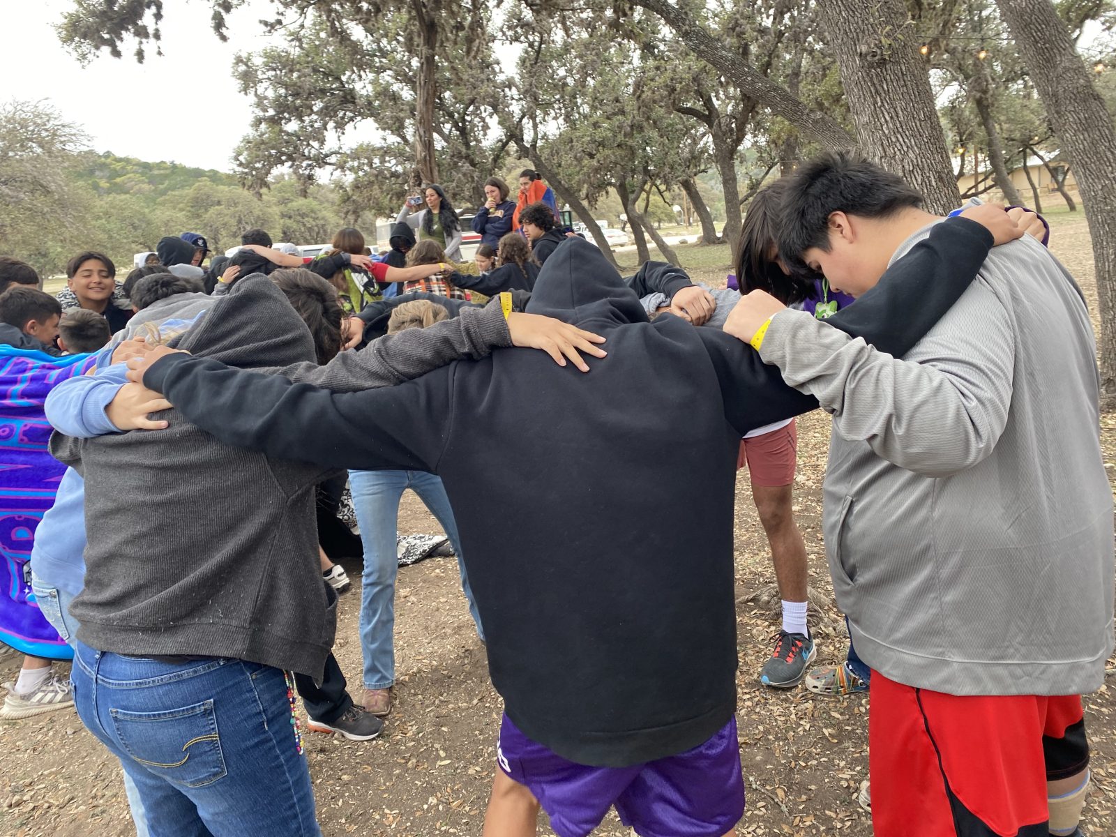 FBC students gathered in prayer with their arms around one another at camp
